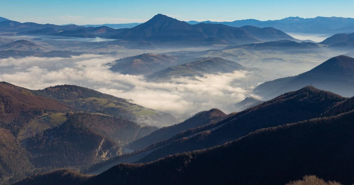A breathtaking view of mountain ranges blanketed by clouds under a clear blue sky.
