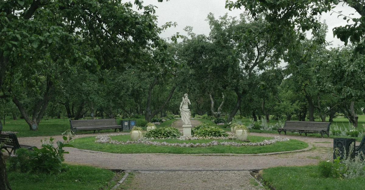 Peaceful garden scene featuring a statue surrounded by lush greenery and benches.