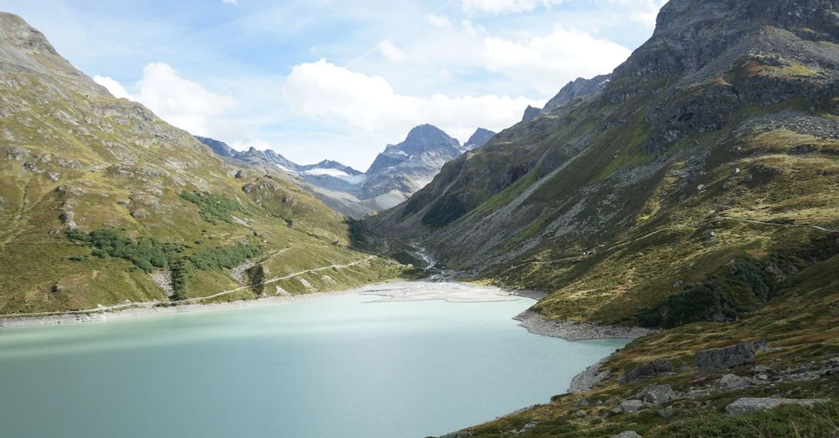 A breathtaking view of an alpine lake surrounded by majestic mountains under a blue sky.
