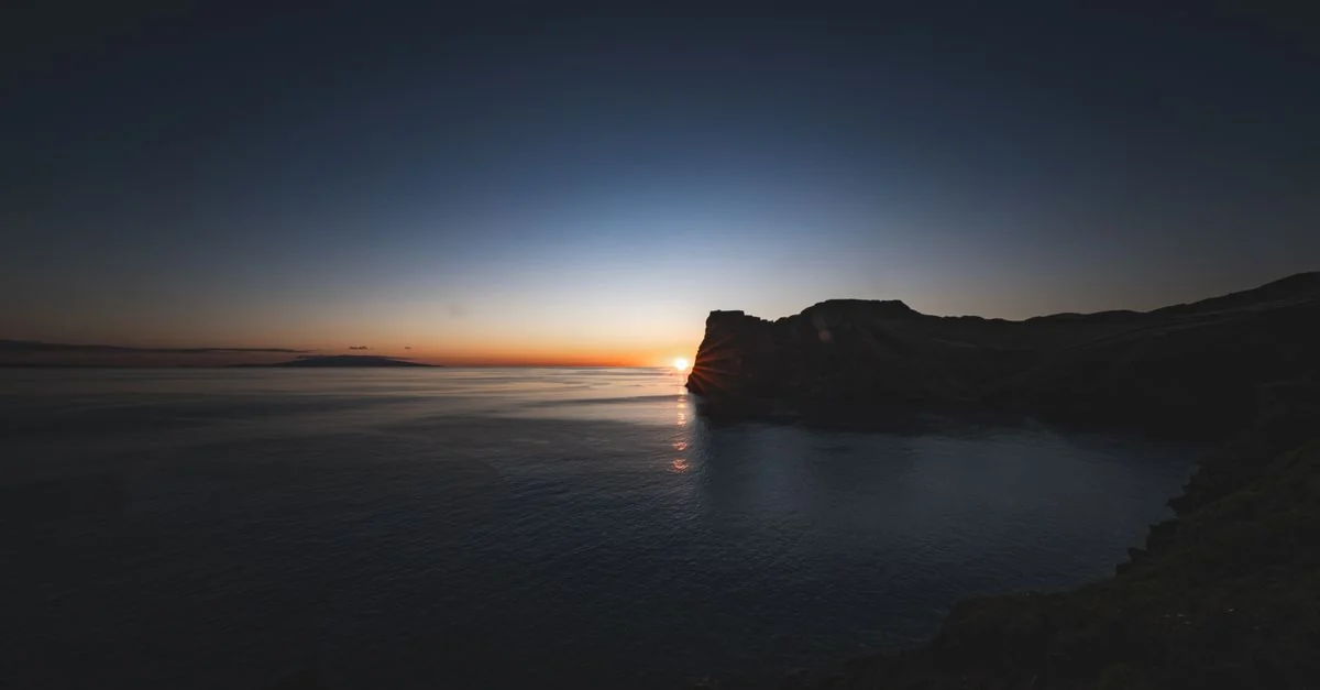 Serene twilight view of a sunset over coastal cliffs with vibrant colors.